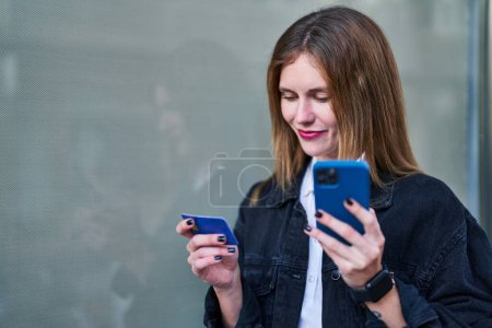 Foto de Mujer rubia joven de compras con teléfono inteligente y tarjeta de crédito en la calle - Imagen libre de derechos