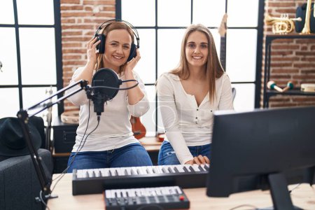 Photo for Two women musicians singing song playing piano at music studio - Royalty Free Image