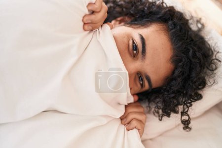 Photo for Young latin man covering mouth lying on bed at bedroom - Royalty Free Image