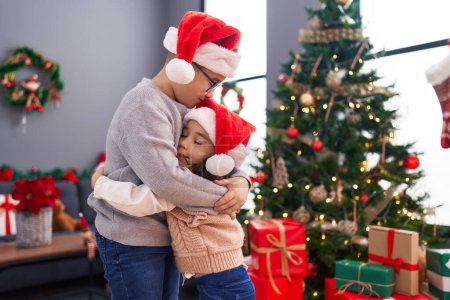 Téléchargez les photos : Frère et sœur s'embrassant et s'embrassant debout par des cadeaux de Noël à la maison - en image libre de droit