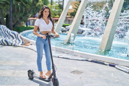 Photo for Young hispanic woman smiling confident using e-scooter at park - Royalty Free Image