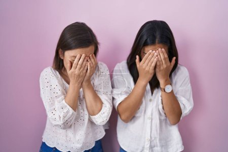 Foto de Madre e hija hispanas junto con expresión triste cubriendo la cara con las manos mientras lloran. concepto de depresión. - Imagen libre de derechos