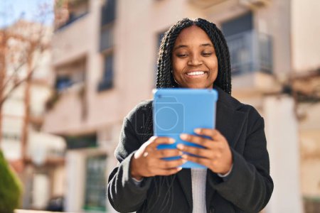 Foto de Mujer afroamericana sonriendo confiada usando touchpad en la calle - Imagen libre de derechos