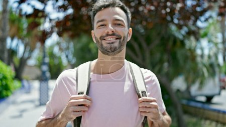 Foto de Joven turista hispano sonriendo confiado usando mochila en el parque - Imagen libre de derechos