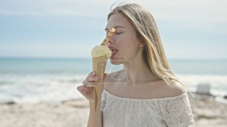 Photo for Young blonde woman tourist eating ice cream at beach - Royalty Free Image