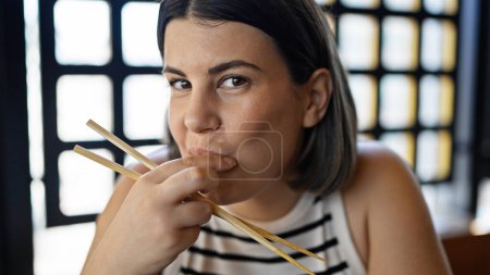 Photo for Young beautiful hispanic woman eating sushi at the restaurant - Royalty Free Image
