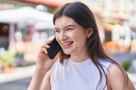 Téléchargez les photos : Jeune femme caucasienne souriant confiant parler sur le smartphone à la rue - en image libre de droit