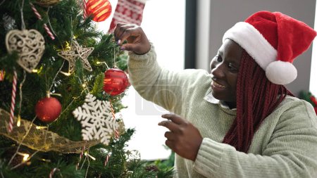 Photo for African woman with braided hair decorating christmas tree at home - Royalty Free Image