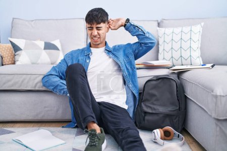 Photo for Young hispanic man sitting on the floor studying for university stretching back, tired and relaxed, sleepy and yawning for early morning - Royalty Free Image