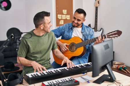 Two men musicians playing piano and classical guitar at music studio