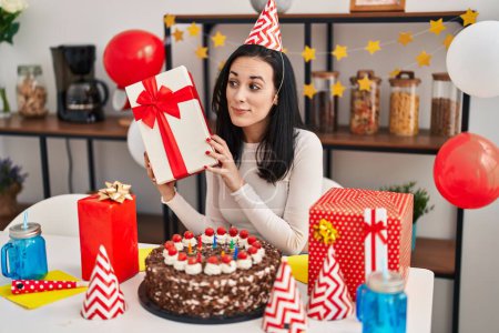 Photo for Young caucasian woman holding gift celebrating birthday at home - Royalty Free Image