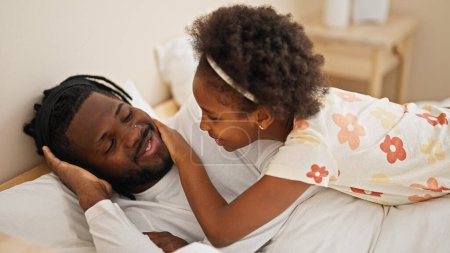 Téléchargez les photos : Afro-américain père et fille couché sur le lit dormir se réveiller dans la chambre - en image libre de droit
