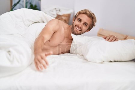 Foto de Joven hombre sonriendo confiado acostado en la cama en el dormitorio - Imagen libre de derechos