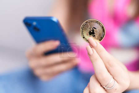 Photo for Young caucasian woman using smartphone holding uniswap coin at home - Royalty Free Image
