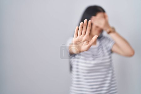 Photo for Young brunette woman wearing striped t shirt covering eyes with hands and doing stop gesture with sad and fear expression. embarrassed and negative concept. - Royalty Free Image