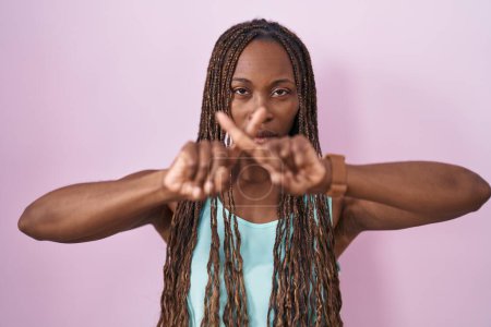 Téléchargez les photos : Femme afro-américaine debout sur fond rose expression de rejet croisant les doigts faisant signe négatif - en image libre de droit