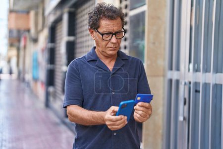 Foto de Hombre de mediana edad usando teléfono inteligente y tarjeta de crédito en la calle - Imagen libre de derechos