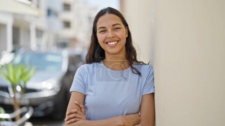 Téléchargez les photos : Femme afro-américaine souriante confiante debout avec les bras croisés geste à la rue - en image libre de droit