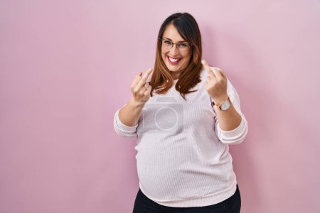 Foto de Pregnant woman standing over pink background showing middle finger doing fuck you bad expression, provocation and rude attitude. screaming excited - Imagen libre de derechos