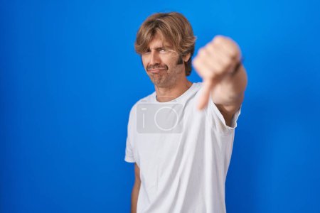 Photo for Middle age man standing over blue background looking unhappy and angry showing rejection and negative with thumbs down gesture. bad expression. - Royalty Free Image