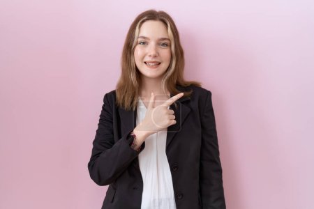 Téléchargez les photos : Jeune femme d'affaires caucasienne portant une veste noire gaie avec un sourire sur le visage pointant avec la main et le doigt sur le côté avec une expression heureuse et naturelle - en image libre de droit