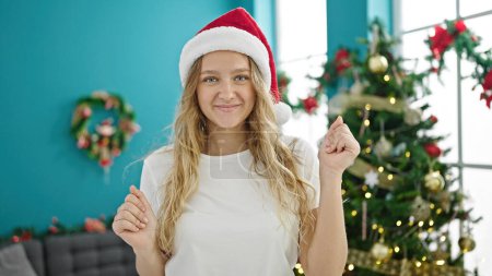 Téléchargez les photos : Jeune femme blonde célébrant Noël dansant à la maison - en image libre de droit