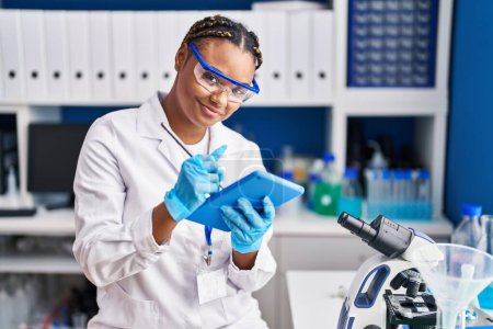 Téléchargez les photos : Femme scientifique afro-américaine utilisant le pavé tactile au laboratoire - en image libre de droit