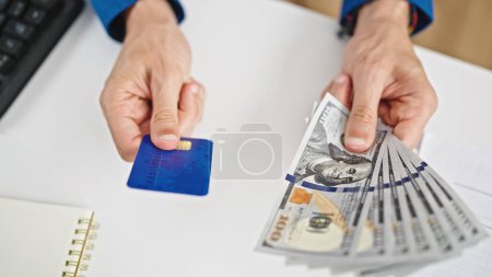 Photo for Young hispanic man holding dollars and credit card at the office - Royalty Free Image