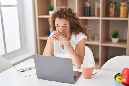 Téléchargez les photos : Jeune belle femme hispanique stressée en utilisant un ordinateur portable assis sur la table à la maison - en image libre de droit