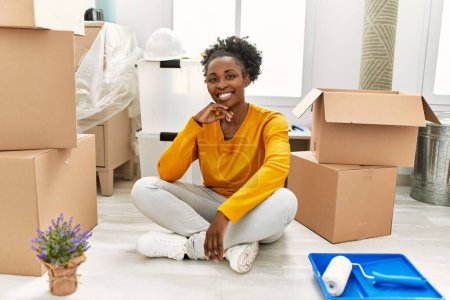 Foto de African american woman smiling confident sitting on floor at new home - Imagen libre de derechos