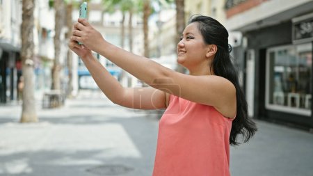 Foto de Joven mujer china sonriendo confiado haciendo foto por el teléfono inteligente en la calle - Imagen libre de derechos