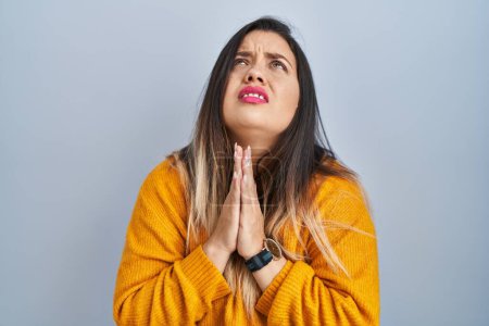 Photo for Young hispanic woman standing over isolated background begging and praying with hands together with hope expression on face very emotional and worried. begging. - Royalty Free Image