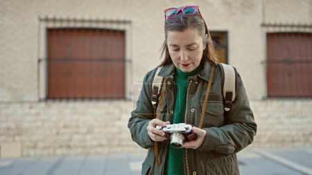 Foto de Mujer hispana madura con turista de pelo gris con mochila sosteniendo cámara vintage en la calle - Imagen libre de derechos