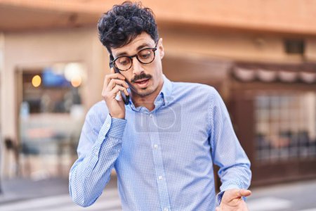 Téléchargez les photos : Young caucasian man talking on the smartphone with serious expression at street - en image libre de droit