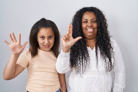 Photo for Mother and young daughter standing over white background showing and pointing up with fingers number eight while smiling confident and happy. - Royalty Free Image