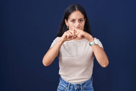 Téléchargez les photos : Jeune femme hispanique debout sur fond bleu expression de rejet croisant les doigts faisant signe négatif - en image libre de droit