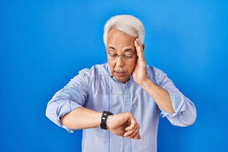 Photo for Hispanic senior man wearing glasses looking at the watch time worried, afraid of getting late - Royalty Free Image