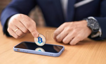 Photo for Young hispanic man business worker insert bitcoin on smartphone at office - Royalty Free Image