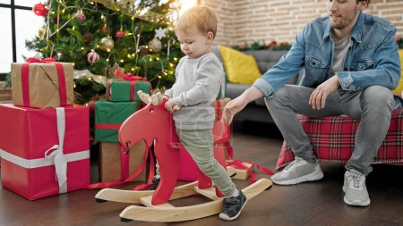 Photo for Father and son celebrating christmas playing with reindeer rocking at home - Royalty Free Image