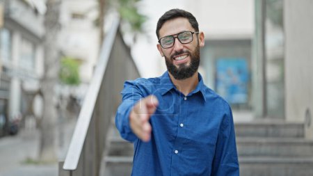Téléchargez les photos : Jeune homme hispanique homme d'affaires travailleur souriant confiant serrant la main à la rue - en image libre de droit