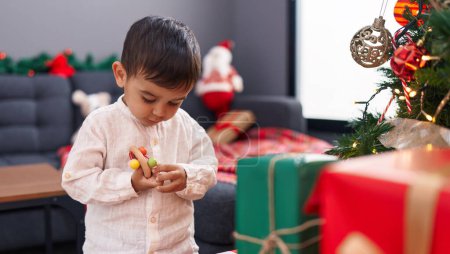 Foto de Adorable niño hispano decorando el árbol de Navidad en casa - Imagen libre de derechos
