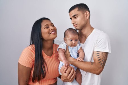 Photo for Young hispanic couple with baby standing together over isolated background looking sleepy and tired, exhausted for fatigue and hangover, lazy eyes in the morning. - Royalty Free Image