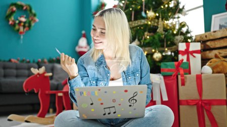 Téléchargez les photos : Jeune belle femme hispanique faisant du shopping avec ordinateur portable et carte de crédit célébrant Noël à la maison - en image libre de droit