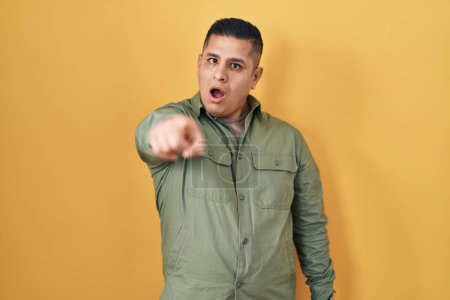 Photo for Hispanic young man standing over yellow background pointing displeased and frustrated to the camera, angry and furious with you - Royalty Free Image