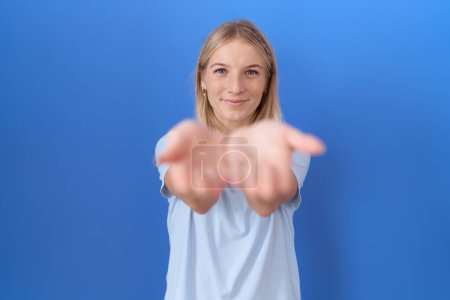 Téléchargez les photos : Jeune femme caucasienne portant un t-shirt bleu décontracté souriant avec les mains paumes ensemble recevant ou donnant geste. maintien et protection - en image libre de droit