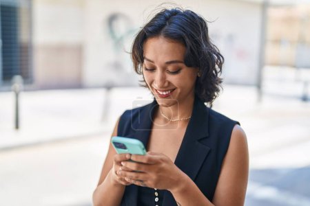 Photo for Young beautiful hispanic woman smiling confident using smartphone at street - Royalty Free Image