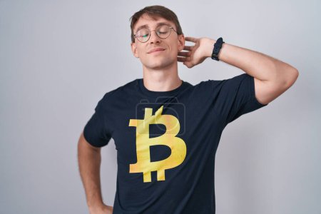 Photo for Caucasian blond man wearing bitcoin t shirt stretching back, tired and relaxed, sleepy and yawning for early morning - Royalty Free Image