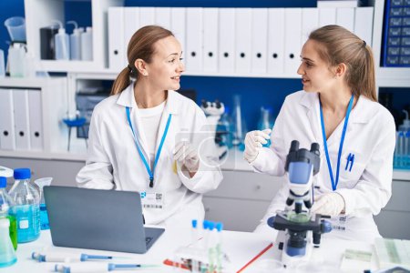 Foto de Dos mujeres científicas usando microscopio y portátil en el laboratorio - Imagen libre de derechos