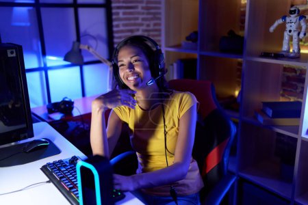 Foto de Young african american woman streamer playing video game using computer at gaming room - Imagen libre de derechos