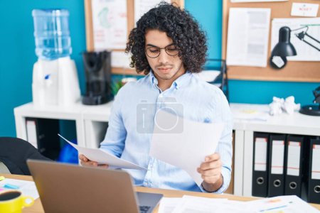 Foto de Joven trabajador de negocios latino utilizando el documento de lectura de computadoras portátiles en la oficina - Imagen libre de derechos